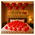 Happy Anniversary bedroom decoration with gold foil letters, red heart foil balloons and romantic balloon setup.