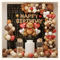 Teddy Bear birthday balloon decoration featuring teddy bear foil balloon, rose gold Happy Birthday foil letters, black fringe curtain, fairy lights, brown, nude and cream balloon garland with heart foil balloons.