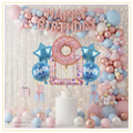 Pastel donut birthday decoration setup with rose gold Happy Birthday foil balloons, pastel pink and blue balloon arch, donut foil balloon, candy balloons and birthday backdrop.