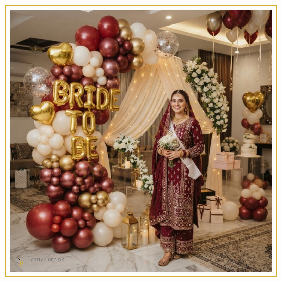 Sindhi Royal Bride decoration with maroon, red, gold and ivory balloon arch, gold Bride To Be foil letters, premium floral décor and elegant bridal shower backdrop.